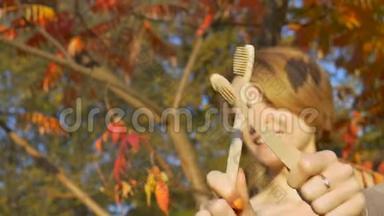 金黄<strong>短发</strong>的<strong>小女孩</strong>，在秋天阳光明媚的天气里，拿着一把竹制牙刷在户外